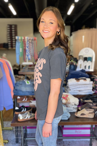 Poppy & Pine Jesus Loves You Smiley Puff Tee in charcoal with tan puff ink lettering, model wearing size small