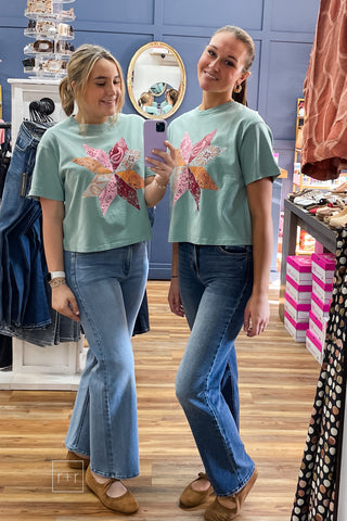 Two models in the Poppy & Pine Bandana Pinwheel Cropped Tee in sage green, styled with flare jeans and brown suede ballet flats