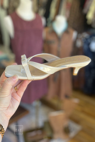 Alternate side view of Corkys Dainty ivory kitten heel sandal showing 2.25 inch heel and open back, held in hand