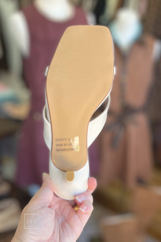 Sole view of Corkys Dainty ivory kitten heel sandal showing bottom and heel, held in hand