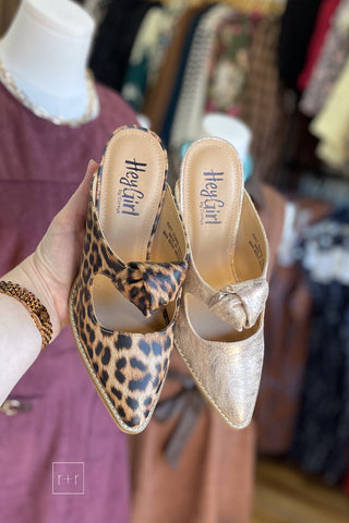 Corkys Knot Gonna Happen heeled mule in gold and leopard held side by side, showing the knot detail and peep cutout