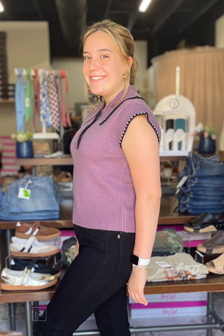 Side profile of the dusty plum knit polo top showing the pointed collar and cap sleeve silhouette.