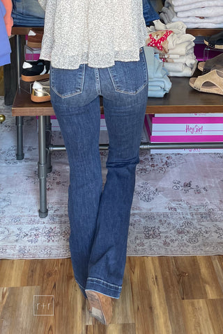 Back view of Judy Blue 82637 high waist dark wash trouser flare jeans with one leg stepped forward