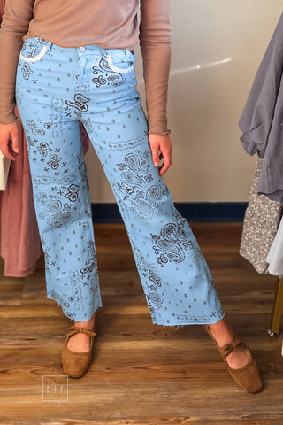 Front view of Poppy & Pine light blue paisley bandana high rise jeans with brown print and raw fray hem