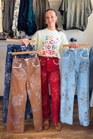 Model holding Poppy & Pine paisley bandana fray hem jeans in brown, navy and light blue while wearing the red pair