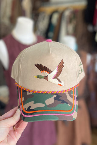 Tan baseball cap with flying mallard graphic, camo bill with rope detail, and pink and orange trim