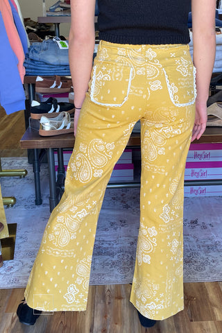 back view Poppy & Pine mustard paisley bandana high rise jeans styled with a black knit sleeveless sweater and black ballet flats