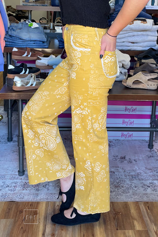side view Poppy & Pine mustard paisley bandana high rise jeans styled with a black knit sleeveless sweater and black ballet flats