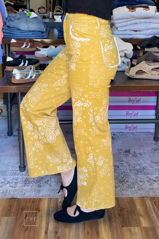 side view Poppy & Pine mustard paisley bandana high rise jeans styled with a black knit sleeveless sweater and black ballet flats