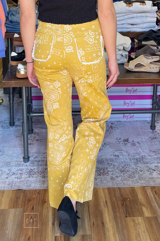 back view Poppy & Pine mustard paisley bandana high rise jeans styled with a black knit sleeveless sweater and black ballet flats