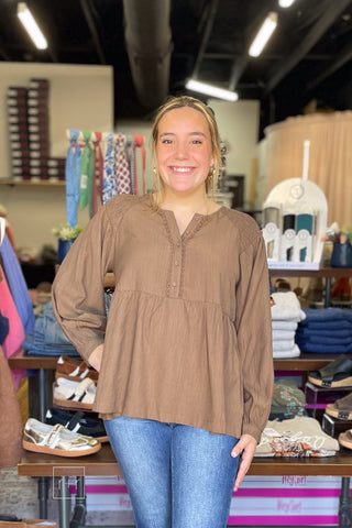 Model wearing the Umgee N7223 almond brown crinkle babydoll top with Risen high rise flare jeans, front view