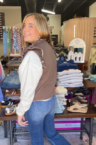 Angled view of the Umgee C6829 mocha quilted vest showing the ruffle shoulder detail, styled with Risen High Rise Flare Jeans PF21438