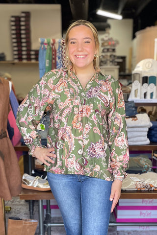 Model wearing the Umgee N7201 floral paisley smocked long sleeve blouse with Risen PF21438 High Rise Flare Jeans and Hey Girl by Corkys Layover Ballet Flats with Bow Detail in camel, front view with hands on hips