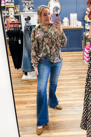 Full-length mirror view of the Umgee N7201 floral smocked blouse styled with Risen PF21438 High Rise Flare Jeans and camel Hey Girl by Corkys Layover Ballet Flats