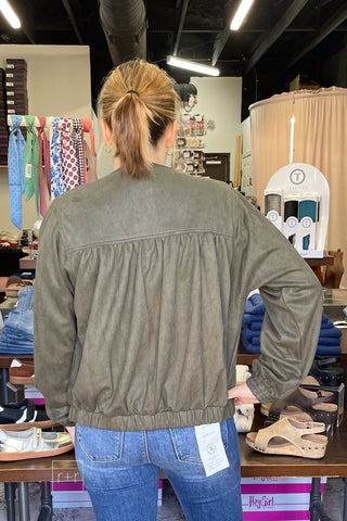 Back view of the Umgee Shayla olive suede-look zip up jacket N7068, hand on hip, showing the gathered back and hem