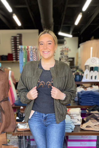 Closeup of the Umgee Shayla olive suede-look ruched zip up jacket N7068 worn open over the Double Horses Cropped Graphic Tee by Zutter and dark wash jeans