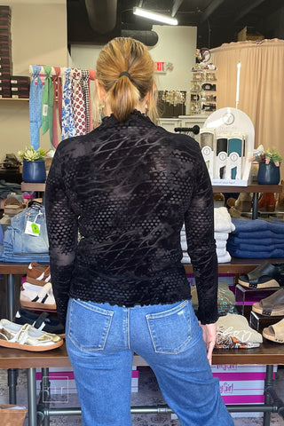 Straight back view of the Umgee D1256 black velvet burnout mock neck top with lettuce-edge hem, worn with Risen High Rise Wide Leg Jeans