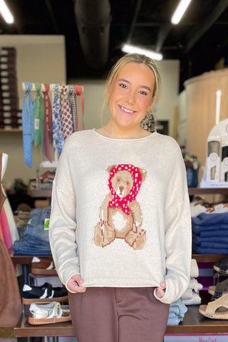 Close-up of model holding out the Wishlist Scarf Teddy Bear Graphic Knit Sweater (WL26-13104) to show the intarsia teddy bear graphic design